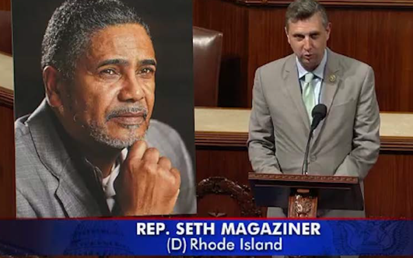 Magaziner speaks next to a large photograph of Cedric