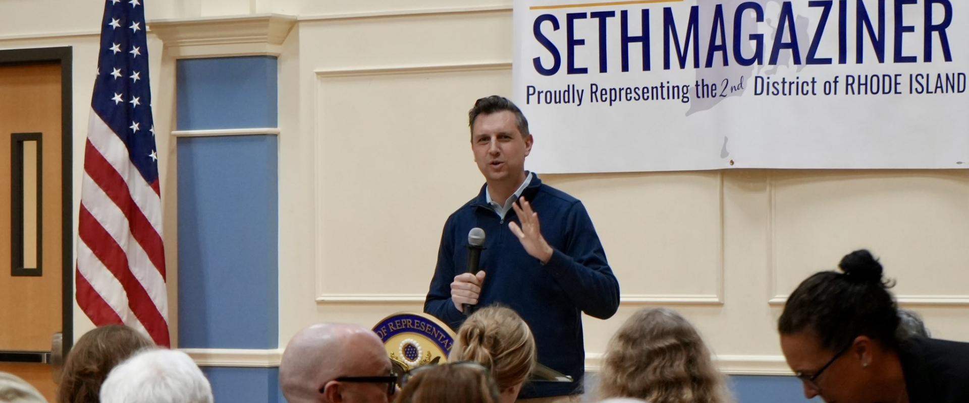 Magaziner stands and speaks in front of audience at town hall