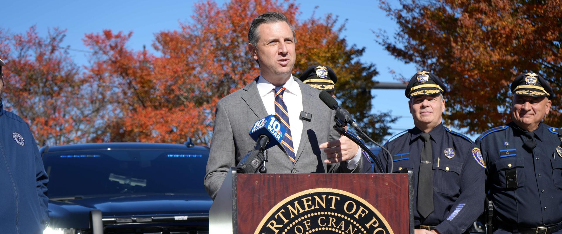 Representative Magaziner speaking at a podium with the Cranston Police Department